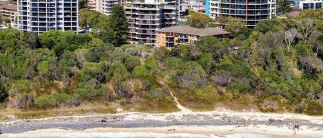 A coastal area with multiple high-rise buildings, a sandy beach, and clear turquoise waters.