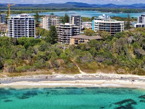 Eine Küstenlandschaft mit mehreren Hochhäusern, einem Sandstrand und klarem, türkisblauem Wasser.