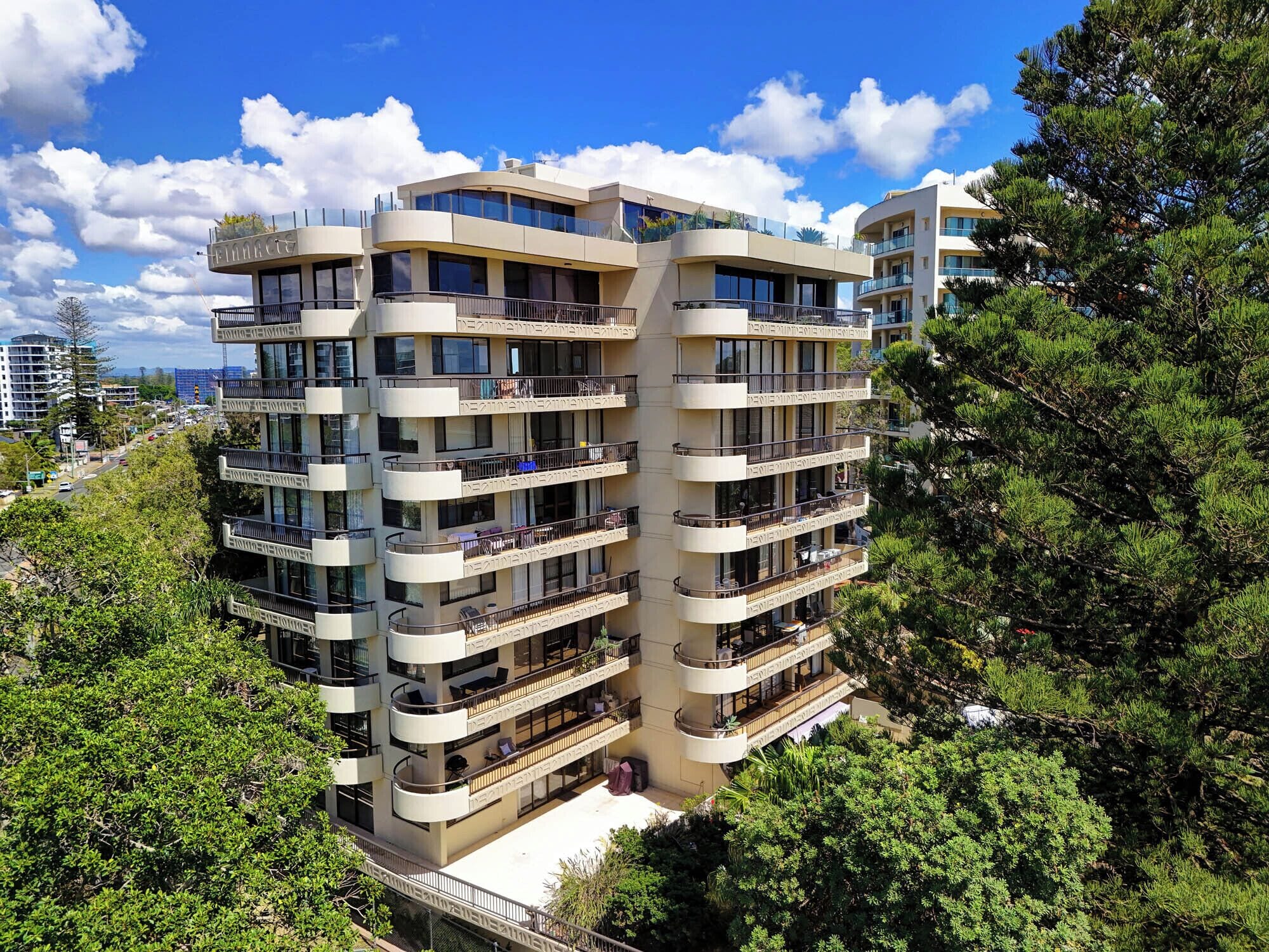 A multi-story residential building with balconies, surrounded by trees.