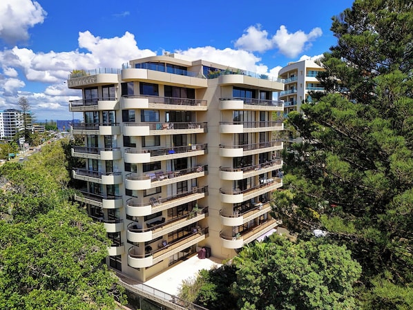 Un immeuble résidentiel à plusieurs étages, doté de balcons et entouré d’arbres.