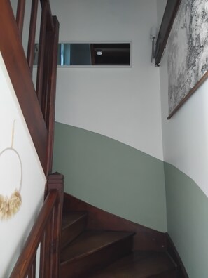 A staircase with wooden railings, a green wall, and a small vent on the wall.