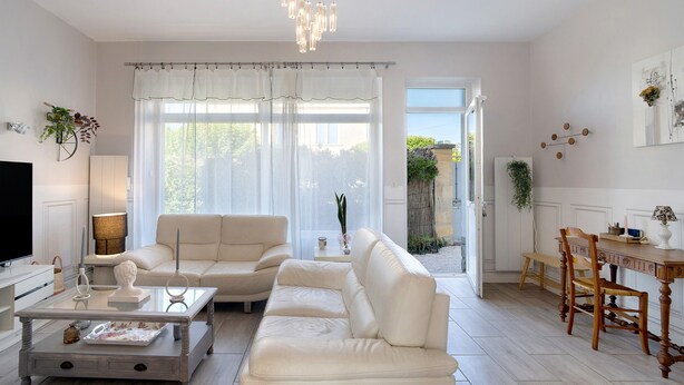 A living room with a sofa, coffee table, and TV. There is a dining area with a table and chairs.