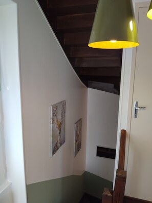Un escalier avec une rampe en bois, un mur vert et deux tableaux encadrés.