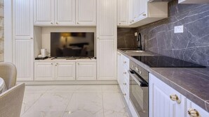 A kitchen with white cabinetry, a built-in oven, and a marble countertop.