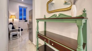 A room with a green console table, a mirror, and a window with blinds.