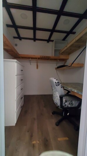 A compact room with a desk, chair, and built-in storage unit.
