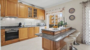 A kitchen with wooden cabinets, a granite countertop, a built-in oven, a microwave, and a sink.
