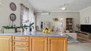 A kitchen with a granite countertop, wooden cabinets, a ceiling fan, and a dining area with a table and chairs.