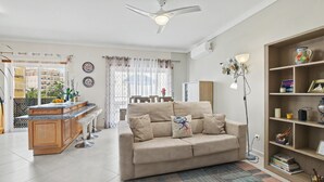A living room with a sofa, a coffee table, a dining area, and a kitchen with a bar.