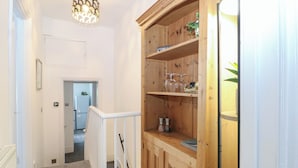 A hallway with a wooden cabinet, a staircase, and a door leading to a kitchen. - Foreshore (Deal)