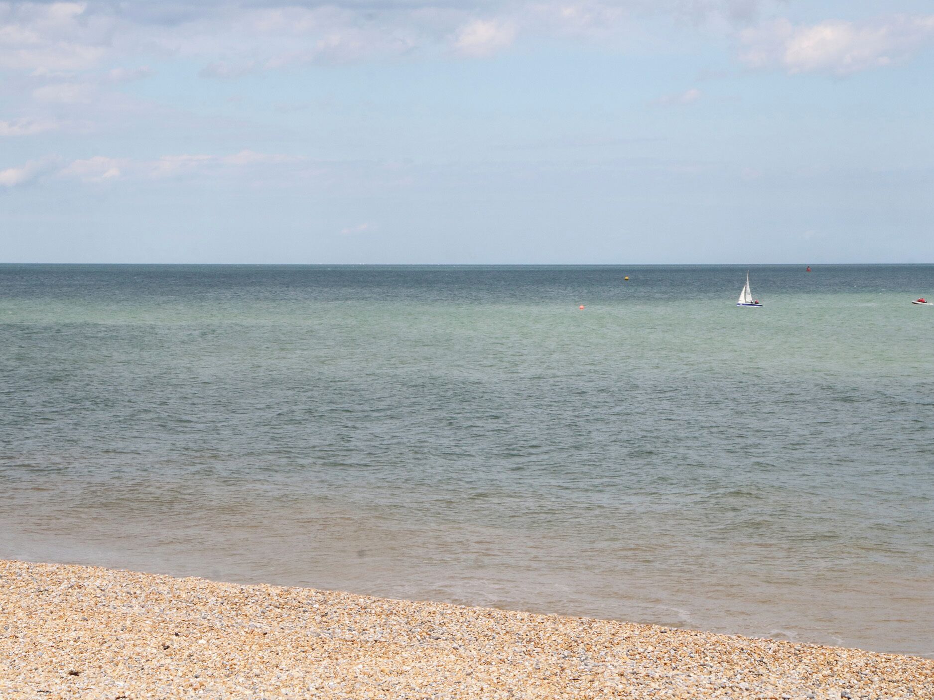 A beach with a pebbly shore and calm sea.