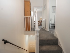 A staircase with a handrail, carpeted steps, and a white door at the bottom.