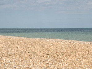 A pebbled beach with clear water and a distant horizon.