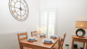 A dining area with a wooden table, chairs, and a wall clock. - Foreshore (Deal)