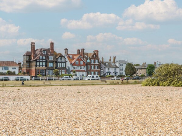 A coastal residential area with houses, a pebbled beach, and a clear sky.