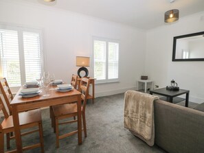 A dining area with a table set for four, a sofa, a small side table, and a lamp. - Foreshore (Deal)