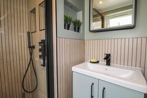 A bathroom with a shower, a sink, and a mirror. - Foreshore (Deal)