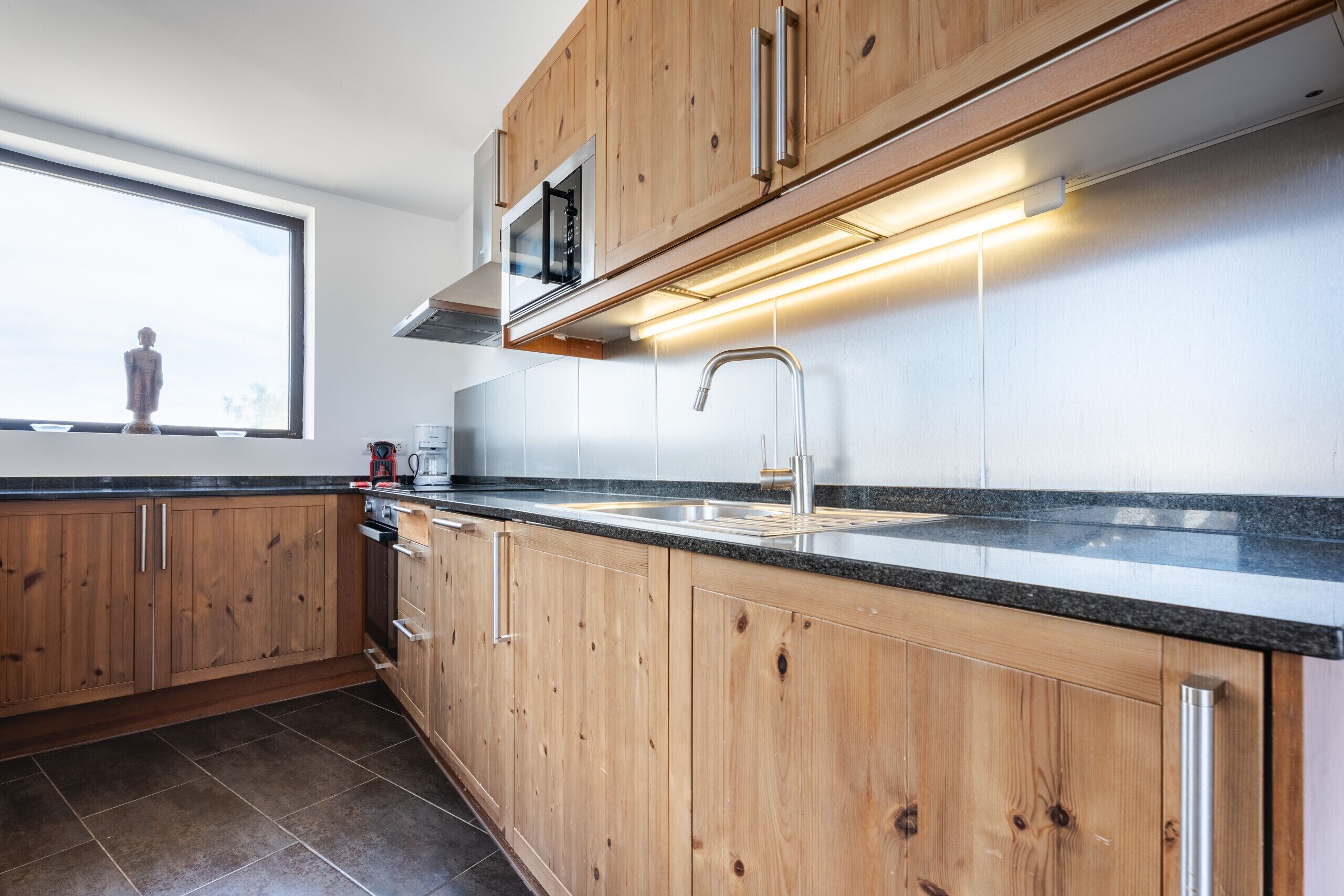 Une cuisine moderne avec des meubles en bois, un évier en acier inoxydable et une fenêtre offrant une belle vue.