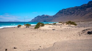 Une plage avec un ciel dégagé, un terrain rocheux et un mât de drapeau.