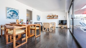 Un salon moderne avec un coin repas, des meubles en bois et des œuvres d’art accrochées aux murs.