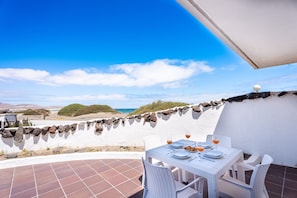 A terrace with a table set for two, overlooking a beach and ocean. - Quicksand • Ocean views • Beach 1 min • LVH (Famara)