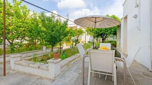 A patio with a table and chairs, a large umbrella, and a garden with trees and plants. - Spacious two-level apartment, ideal for four people, with two bedrooms, two bathrooms, private parking, and a pleasant furnished internatl garden for relaxing outdoors. Located in the center of Campi Salentina, in a quiet residential area, it's just a 15 (Campi Salentina)