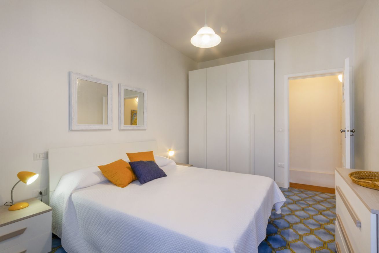 Une chambre à coucher comprenant un lit, des tables de chevet, une armoire et un miroir.