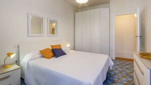 A bedroom with a bed, bedside tables, a wardrobe, and a mirror. - Spacious two-level apartment, ideal for four people, with two bedrooms, two bathrooms, private parking, and a pleasant furnished internatl garden for relaxing outdoors. Located in the center of Campi Salentina, in a quiet residential area, it's just a 15 (Campi Salentina)