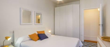 A bedroom with a bed, bedside tables, a wardrobe, and a mirror.