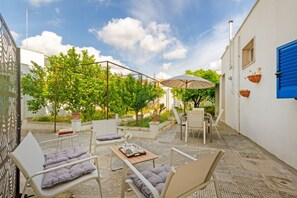 Une terrasse extérieure avec des sièges, une table et une pergola surmontée d’une toiture.
