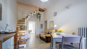 A dining area with a table, chairs, a sofa, and a staircase leading to another room. - Spacious two-level apartment, ideal for four people, with two bedrooms, two bathrooms, private parking, and a pleasant furnished internatl garden for relaxing outdoors. Located in the center of Campi Salentina, in a quiet residential area, it's just a 15 (Campi Salentina)