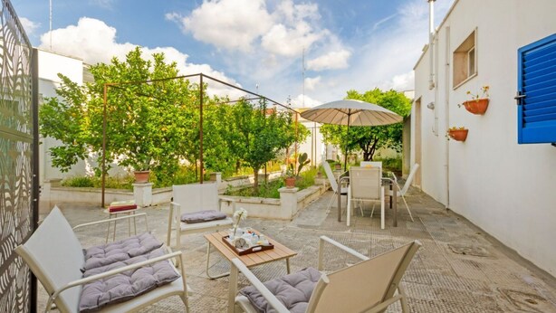 An outdoor patio with seating, a table, and a pergola with a canopy. - Spacious two-level apartment, ideal for four people, with two bedrooms, two bathrooms, private parking, and a pleasant furnished internatl garden for relaxing outdoors. Located in the center of Campi Salentina, in a quiet residential area, it's just a 15 (Campi Salentina)