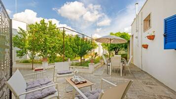 Une terrasse extérieure avec des sièges, une table et une pergola surmontée d’une toiture.