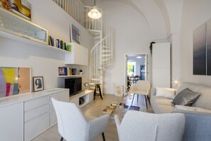 Un salon moderne avec un escalier en colimaçon blanc, un canapé, une table basse et un téléviseur.