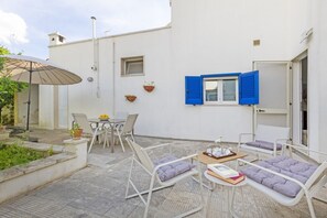 A patio with outdoor furniture, a table with books, and a window with blue shutters. - Spacious two-level apartment, ideal for four people, with two bedrooms, two bathrooms, private parking, and a pleasant furnished internatl garden for relaxing outdoors. Located in the center of Campi Salentina, in a quiet residential area, it's just a 15 (Campi Salentina)
