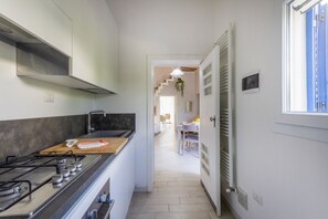 A kitchen with a stove, a wooden countertop, and a view into a dining area. - Spacious two-level apartment, ideal for four people, with two bedrooms, two bathrooms, private parking, and a pleasant furnished internatl garden for relaxing outdoors. Located in the center of Campi Salentina, in a quiet residential area, it's just a 15 (Campi Salentina)