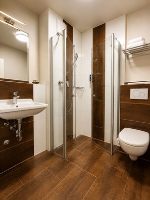 A modern bathroom with a glass-enclosed shower, a sink, and a toilet. - Waidplatz Hotel (Teningen)