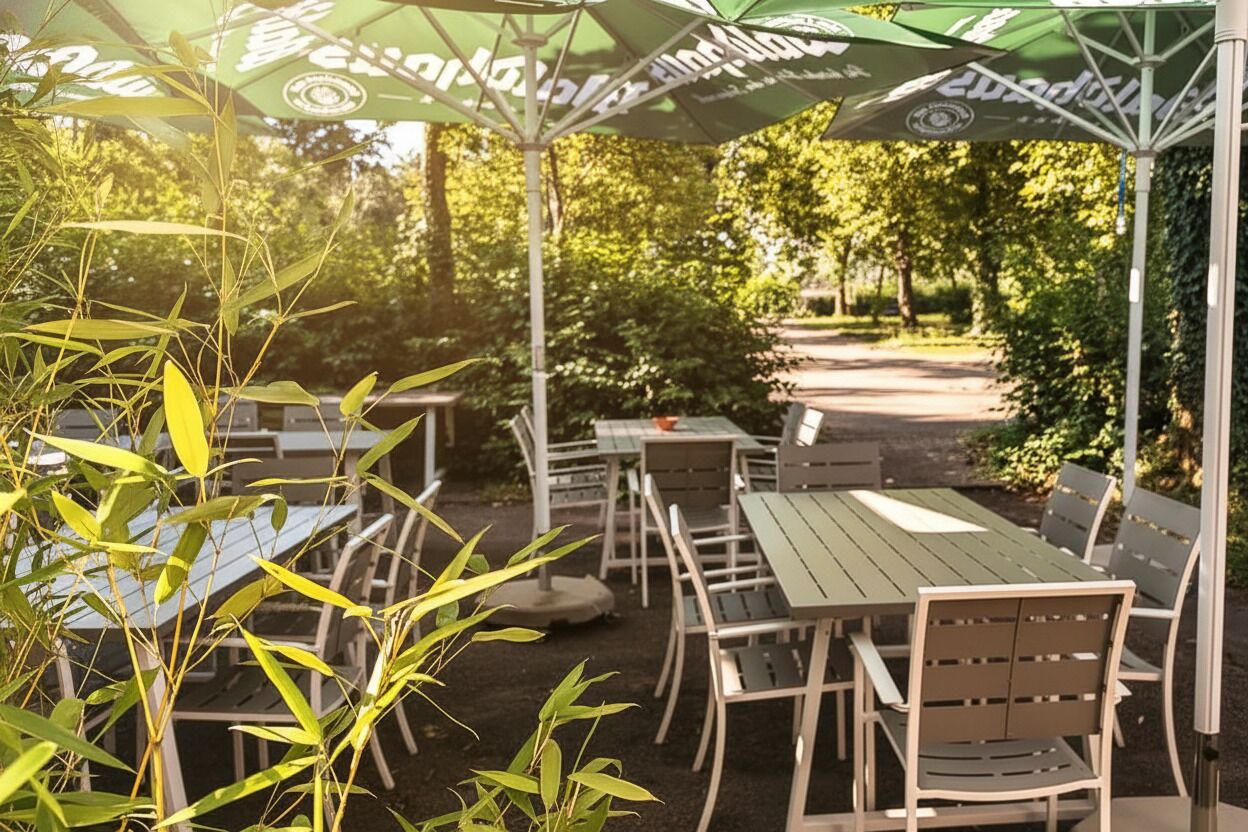 Eine Terrasse im Freien mit Tischen und St ühlen, umgeben von viel Grün.