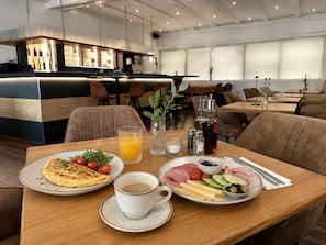 Un desayuno con una mesa para dos, que incluye platos de comida, una taza de café y un vaso de jugo de naranja.