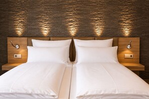 A double bed with a wooden headboard, two bedside tables, and a brick-patterned wall. - Waidplatz Hotel (Teningen)