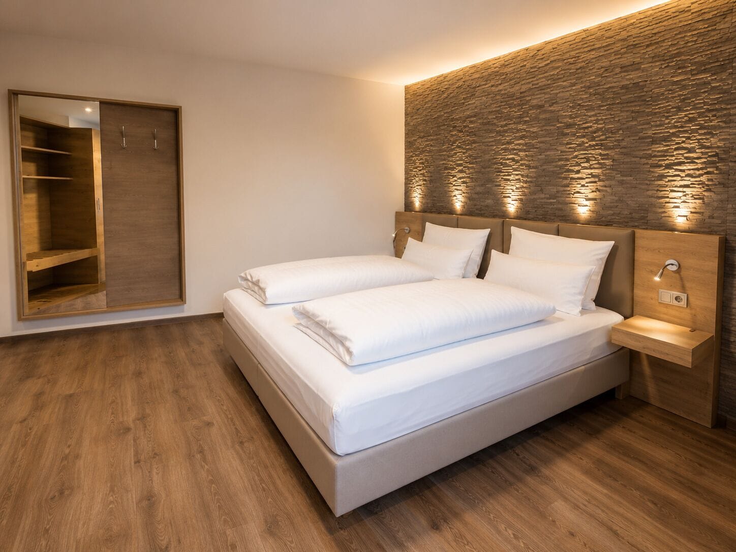 Une chambre à coucher moderne avec un grand lit, une armoire en bois et un mur à motifs.
