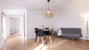 Ein Essbereich mit Tisch, Stühlen, einer Pendelleuchte und einer Couch.
