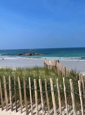 Una platja amb una tanca de fusta i una vista despejada de l'oceà.