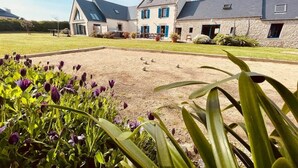 Une grande maison dotée d’une cour pavée, entourée de verdure et de fleurs.