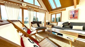 Une pièce avec un lit en mezzanine, un canapé, une table basse et une vue sur l’extérieur.