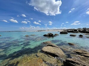 A coastal landscape with clear water, rocks, and distant buildings. - 15pers, 20m from the sea, jaccuzi, seminars, overnight stay (Kerlouan)