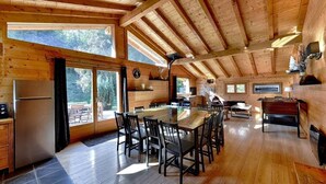 L’intérieur d’un chalet en bois comprend un coin repas, une cuisine et de grandes fenêtres.