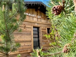 Un chalet in legno con un cartello che riporta 'CHALET 4C' e una porta nera.