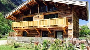 A wooden chalet with a balcony, surrounded by a fenced garden. - Chalet 14 pers, jacuzzi, MontBlanc view, 5 bedrooms (Chamonix)