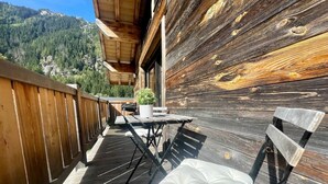 A wooden deck with a table and chairs, overlooking a mountainous landscape. - Chalet 14 pers, jacuzzi, MontBlanc view, 5 bedrooms (Chamonix)